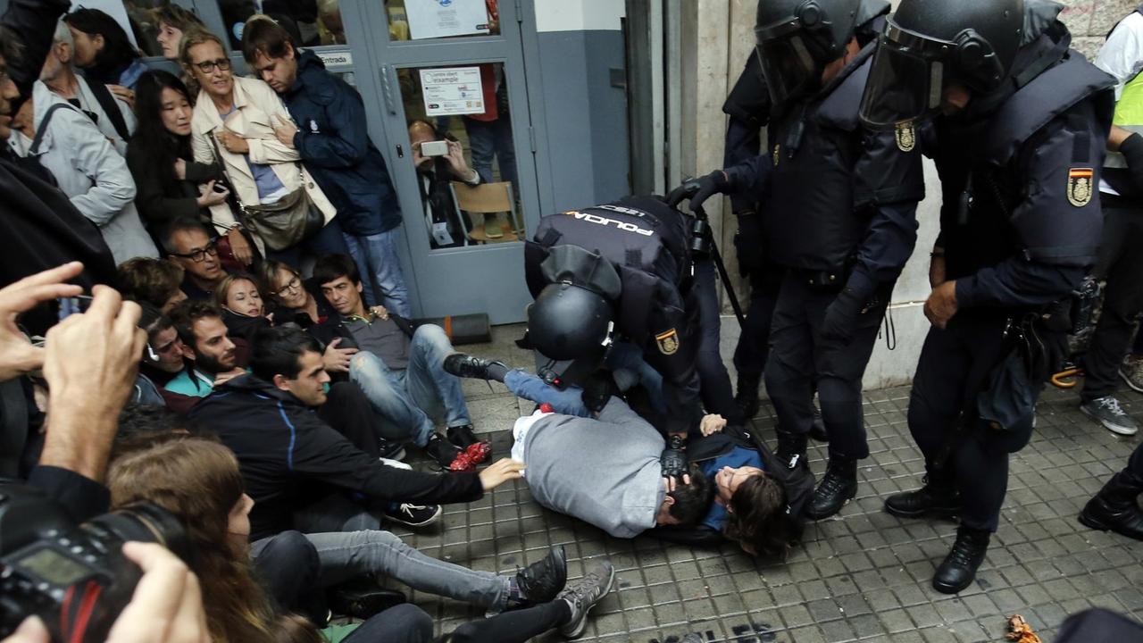 Spanische Polizisten setzen vor einem Wahllokal in Barcelona zwei Menschen fest. Spanische Polizisten setzen vor einem Wahllokal in Barcelona zwei Menschen fest.