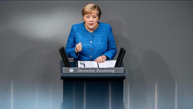Berlin: Bundeskanzlerin Angela Merkel (CDU) spricht bei der Generaldebatte im Deutschen Bundestag. Sie steht hinter einem Rednerpult, vor ihr liegen Manuskripte.