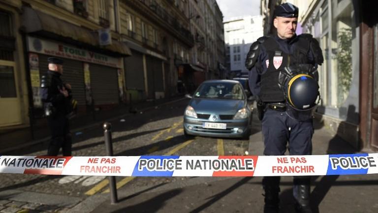 Ein Polizist steht hinter einem rot-weiß-blauen Absperrband mit der Aufschrift "Police Nationale" Ein Polizist steht hinter einem rot-weiß-blauen Absperrband mit der Aufschrift "Police Nationale"
