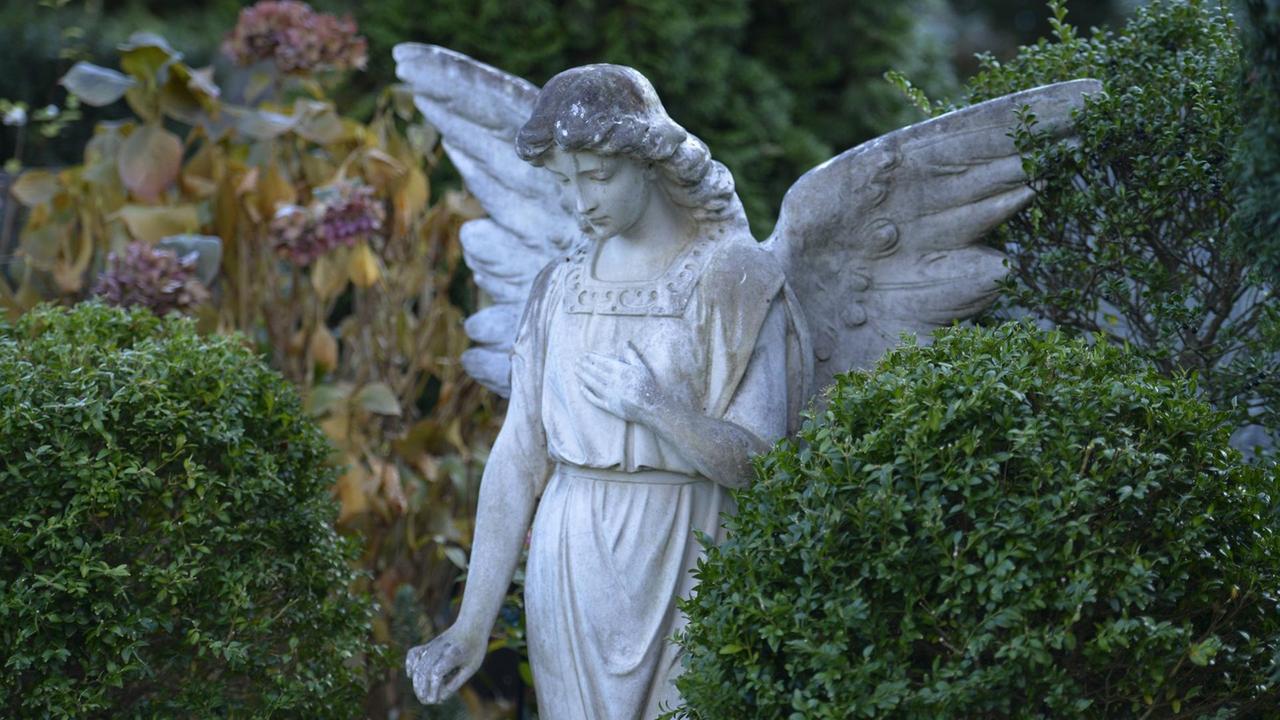Eine weiße, trauernde Engelsfigur auf dem Friedhof in Berlin - Schöneberg. Eine weiße, trauernde Engelsfigur auf dem Friedhof in Berlin - Schöneberg.