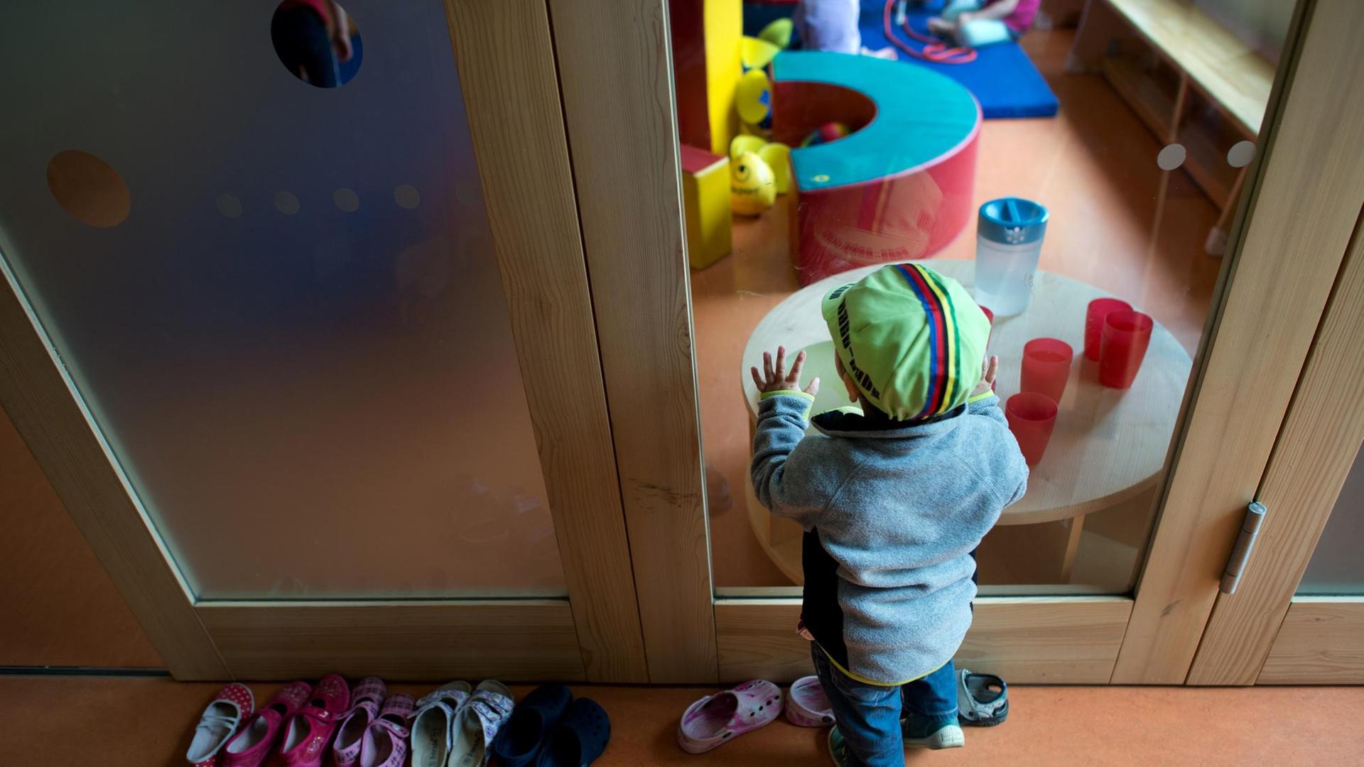 Ein Kleinkind steht vor einer Glasscheibe in einer Kita in Dresden im Mai 2015 Ein Kleinkind steht vor einer Glasscheibe in einer Kita in Dresden im Mai 2015