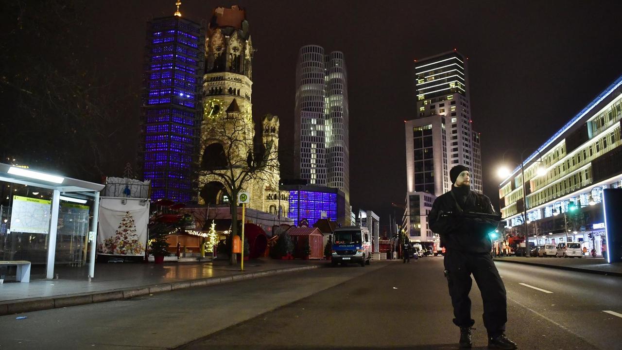 Ein Polizist steht vor der Gedächtniskirche und Hochhäusern in Berlin