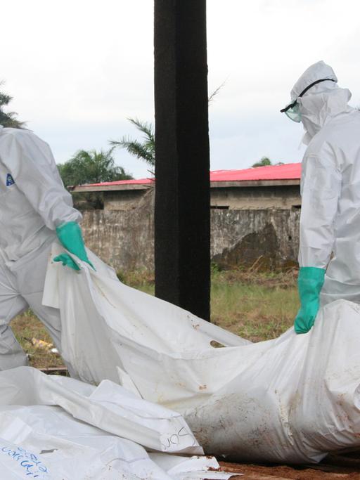 Mitarbeiter von Ärzte ohne Grenzen/Medecins Sans Frontieres (MFS), desinfizieren am 02.09.2014 in Schutzkleidung am Ebola Zentrum der Hilfsorganisation in Monrovia, Liberia, Leichensäcke.