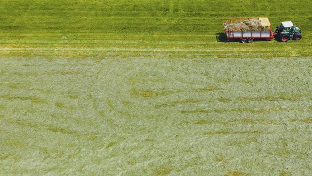 Luftbild von einem Landwirt, der mit seinem Traktor über eine Wiese fährt.