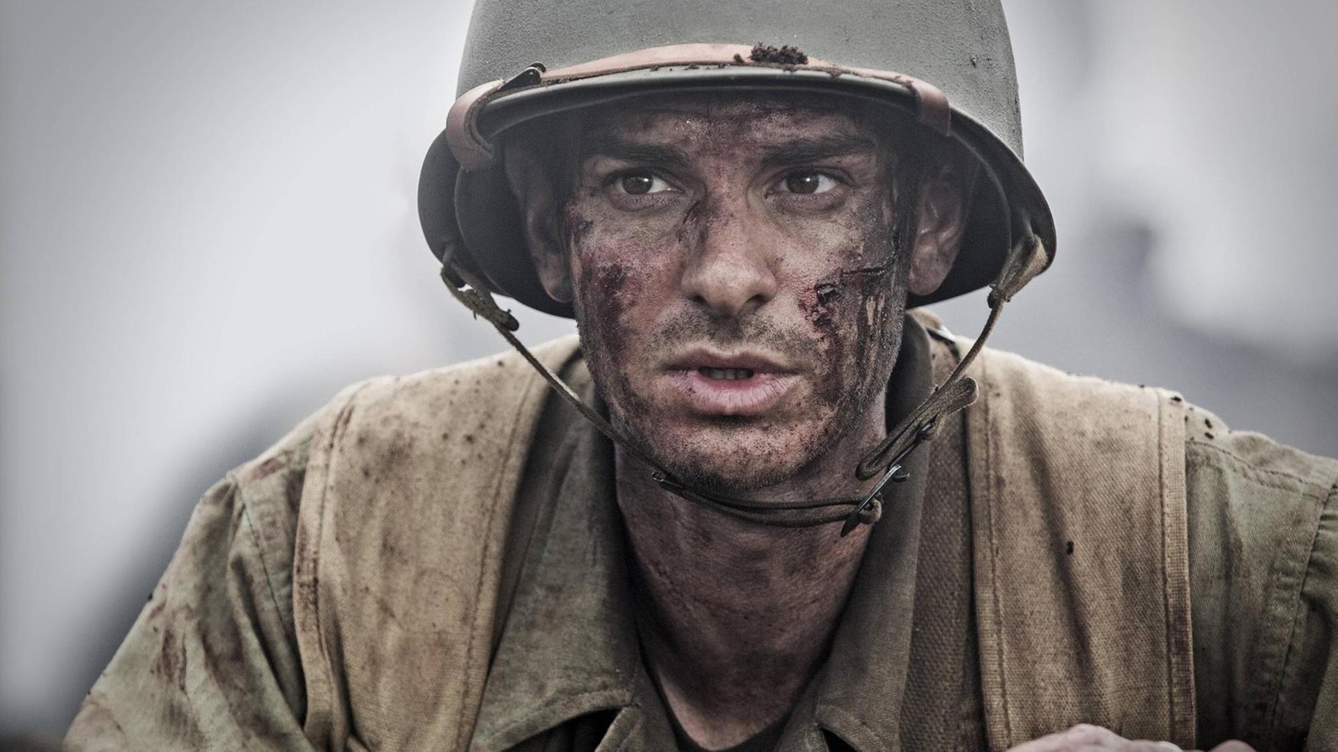 Desmond T. Doss (Andrew Garfield) mit Helm und Kampfanzug im Schützengraben Desmond T. Doss (Andrew Garfield) mit Helm und Kampfanzug im Schützengraben