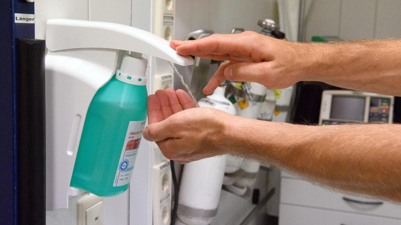 Im Notfallzentrum eines Krankenhauses desinfiziert ein Pfleger seine Hände an einem Spender.