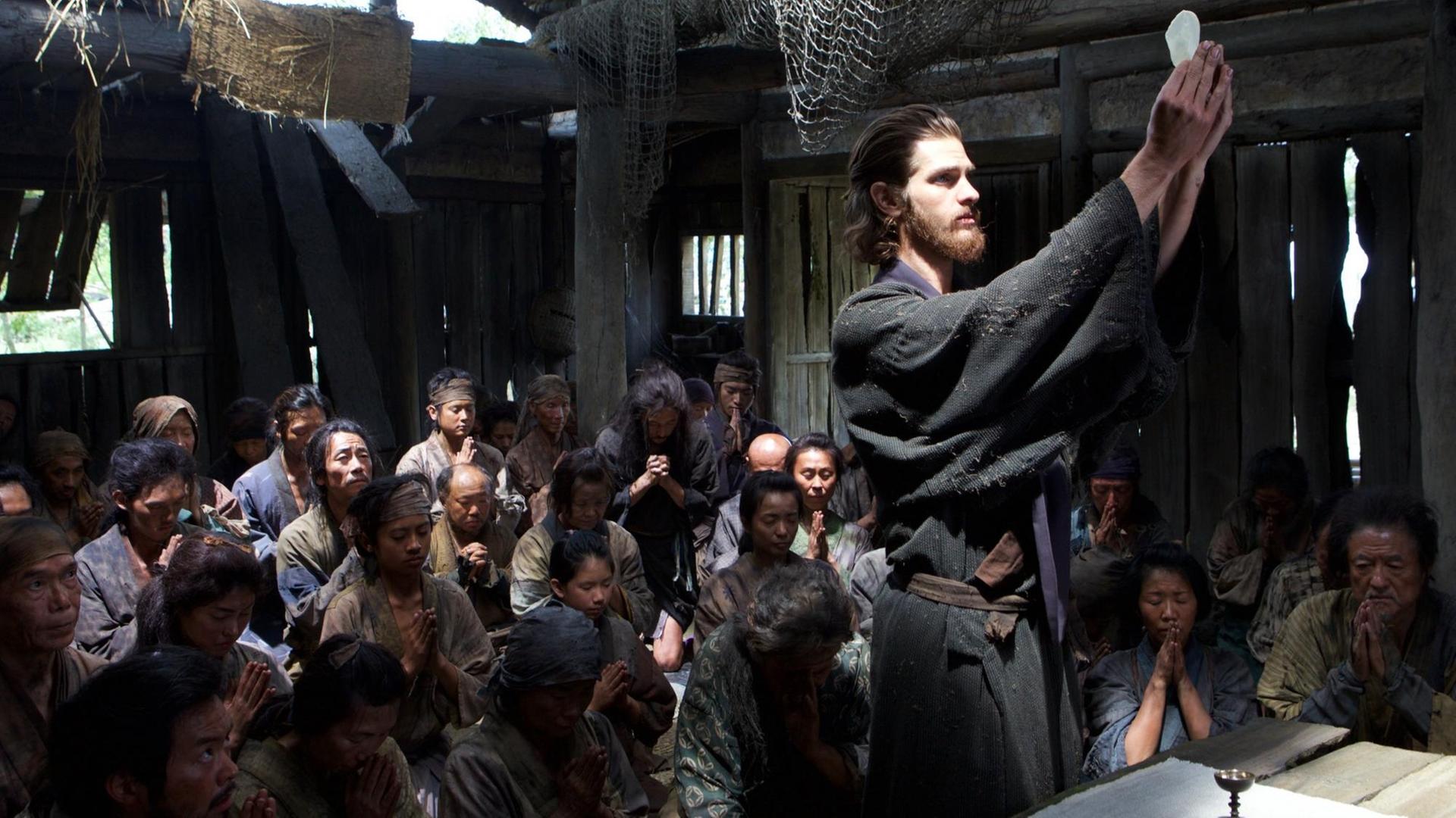 Pater Rodrigues (Andrew Garfield, vorne stehend) zelebriert die Heilige Messe für die christlichen Dorfbewohner im Geheimen. Pater Rodrigues (Andrew Garfield, vorne stehend) zelebriert die Heilige Messe für die christlichen Dorfbewohner im Geheimen.