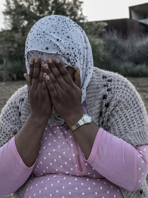 Kalima aus Marokko hält sich beide Hände vor das Gesicht