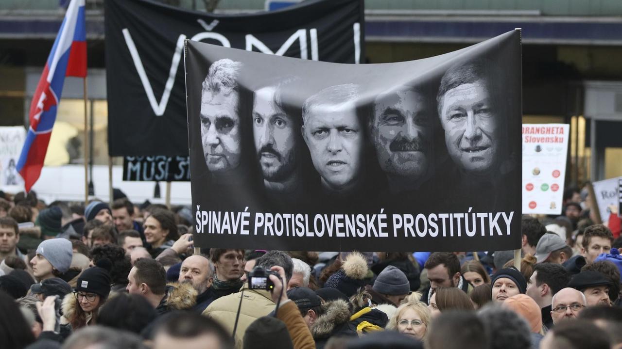 Demonstranten halten während einer Kundgebung gegen die Regierung und die Mafia unter dem Motto «Für eine anständige Slowakei» ein Plakat hoch. Zu sehen sind unter anderem die Gesichter von Ministerpräsident Fico (Mitte), Innenminister Kalinak (2.v.r) und Polizeichef Gaspar (rechts). Demonstranten halten während einer Kundgebung gegen die Regierung und die Mafia unter dem Motto «Für eine anständige Slowakei» ein Plakat hoch. Zu sehen sind unter anderem die Gesichter von Ministerpräsident Fico (Mitte), Innenminister Kalinak (2.v.r) und Polizeichef Gaspar (rechts).