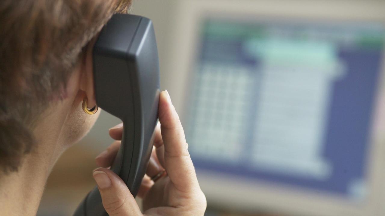 Beratungssgespräch bei der Telefonseelsorge, im Hintergund ein unscharfer Bildschirm, im Vordergrund eine Frau von hinten am Telefon. Beratungssgespräch bei der Telefonseelsorge, im Hintergund ein unscharfer Bildschirm, im Vordergrund eine Frau von hinten am Telefon.