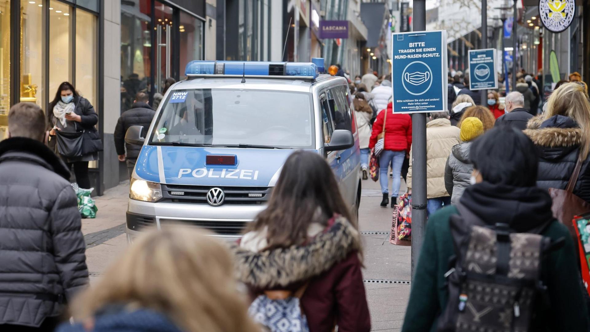 Passanten mit Schutzmasken beim Einkauf im Zentrum der Stadt Essen, links ein Polizeifahrzeug. Passanten mit Schutzmasken beim Einkauf im Zentrum der Stadt Essen, links ein Polizeifahrzeug.