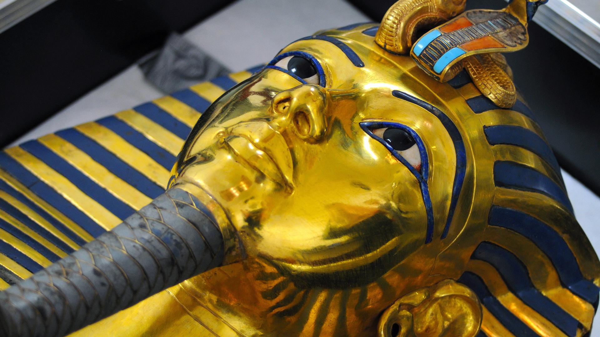 Die Totenmaske von Tutanchamun im Ägyptischen Museum in Kairo. Die Totenmaske des Tutanchamun im Ägyptischen Museum, aufgenommen am 12.10.2015. Durch eine Unachtsamkeit brach im August 2014 der Zeremonialbart der goldenen Totenmaske des Pharaos Tutanchamun im Ägyptischen Museum in Kairo ab. Daraufhin wurde der Bart mit einem Epoxitkleber eilig wieder an die Maske geklebt. Seit einiger Zeit ist ein Restauratorenteam vom Römisch-Germanischen Zentralmuseum in Mainz damit beschäftigt, die Maske zu restaurieren, soweit dies möglich ist. Mit Lindenholzstäbchen wird Millimeter für Millimeter des Klebers mechanisch abgetragen, Ende des Jahres, so hofft man, sei diese Arbeit erledigt. Die Totenmaske von Tutanchamun im Ägyptischen Museum in Kairo. Die Totenmaske des Tutanchamun im Ägyptischen Museum, aufgenommen am 12.10.2015. Durch eine Unachtsamkeit brach im August 2014 der Zeremonialbart der goldenen Totenmaske des Pharaos Tutanchamun im Ägyptischen Museum in Kairo ab. Daraufhin wurde der Bart mit einem Epoxitkleber eilig wieder an die Maske geklebt. Seit einiger Zeit ist ein Restauratorenteam vom Römisch-Germanischen Zentralmuseum in Mainz damit beschäftigt, die Maske zu restaurieren, soweit dies möglich ist. Mit Lindenholzstäbchen wird Millimeter für Millimeter des Klebers mechanisch abgetragen, Ende des Jahres, so hofft man, sei diese Arbeit erledigt.