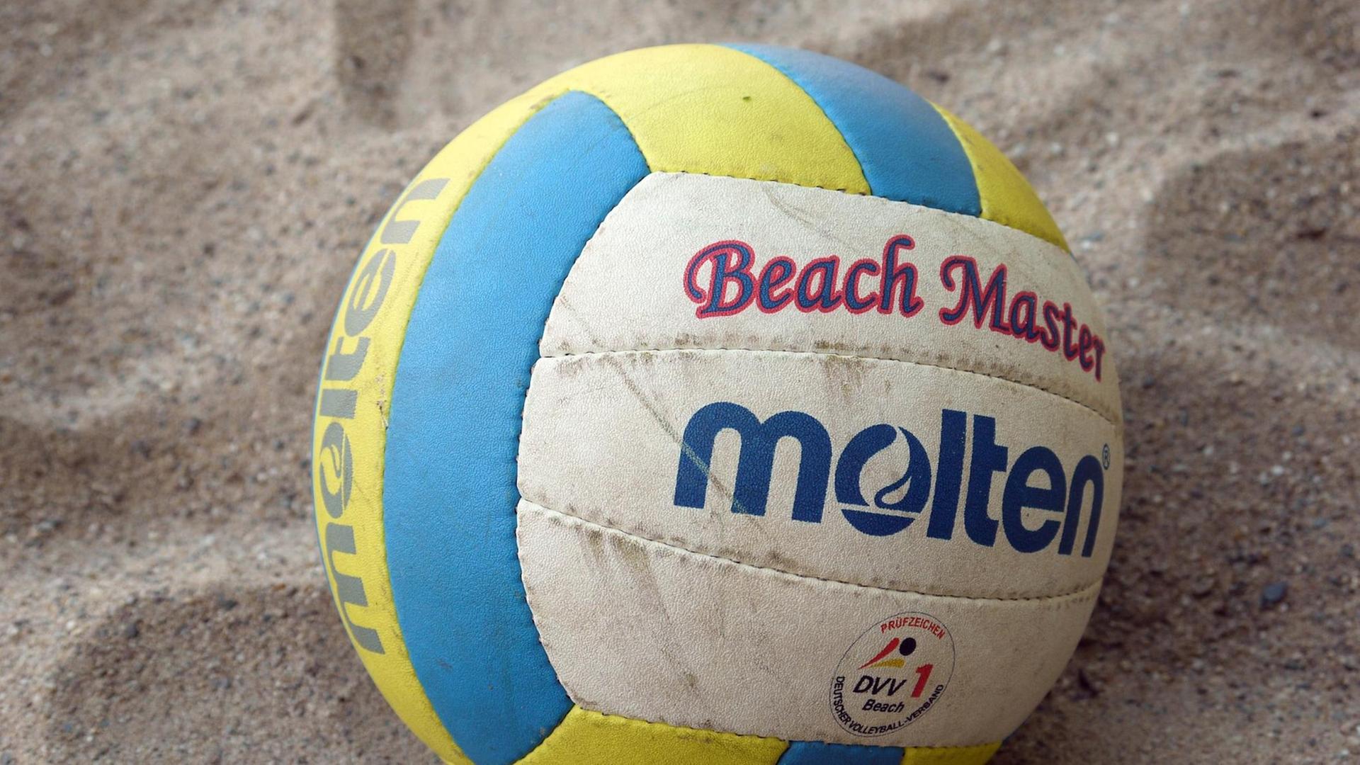 Ein Volleyball liegt auf einem Beachvolleyball-Feld. Ein Volleyball liegt auf einem Beachvolleyball-Feld.