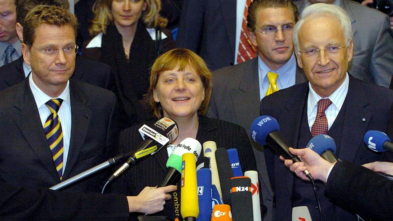 Die CDU-Vorsitzende Angela Merkel, der CSU-Vorsitzende Edmund Stoiber (r) und der FDP-Vorsitzende Guido Westerwelle (l) werden am 14.12.2003 in Berlin vor Beginn der Sitzung des Vermittlungsausschusses von Journalisten interwievt. 
