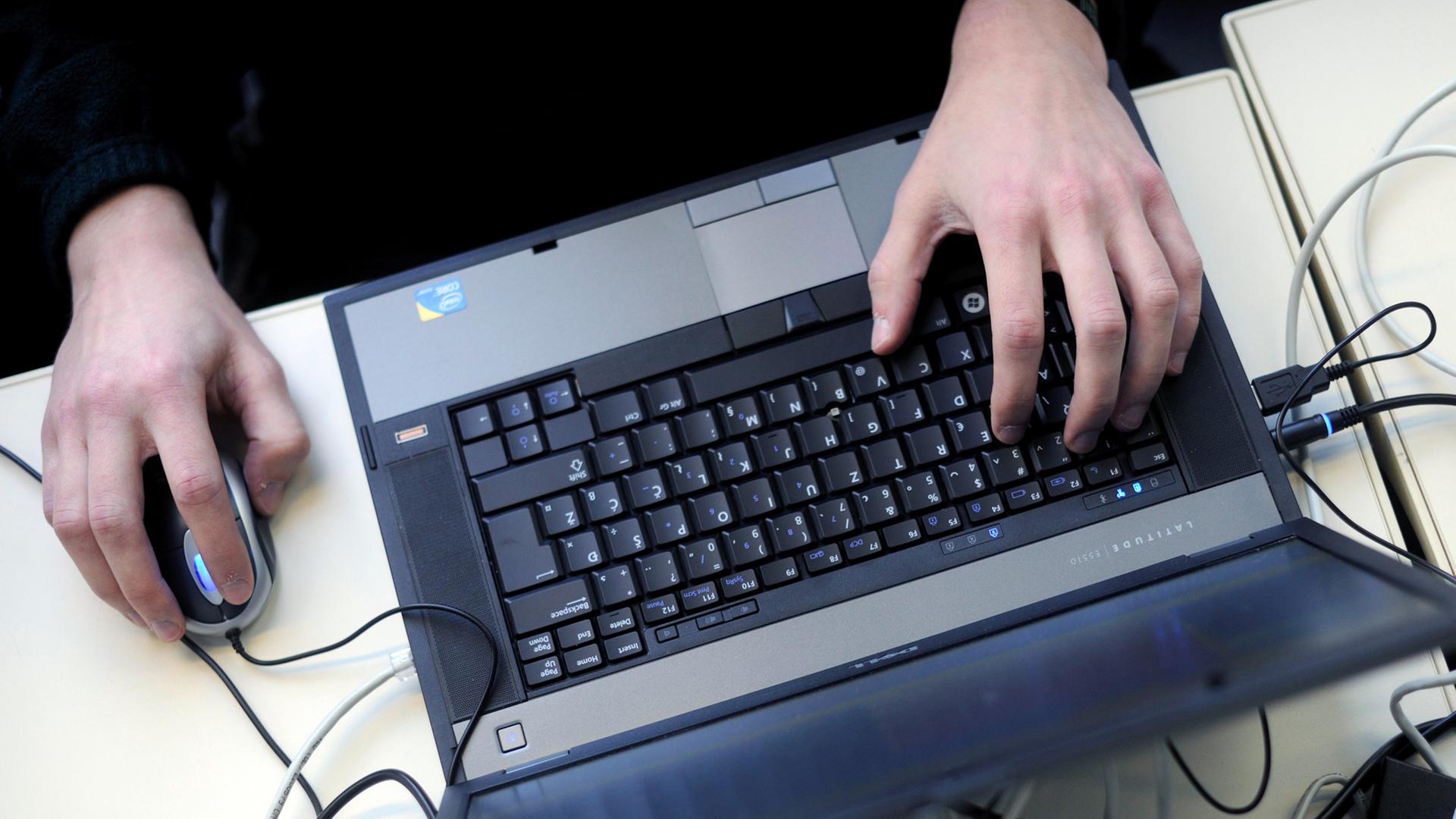 Eine Person bedient einen Laptop mit einer Mouse. Eine Person bedient einen Laptop mit einer Mouse.