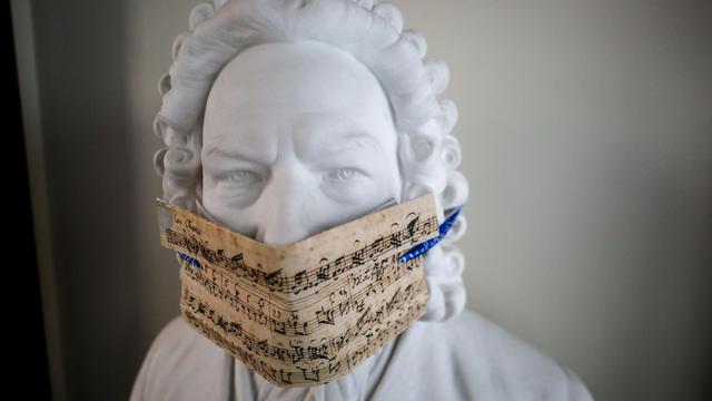 Eine Bach-Büste mit einem Mundschutz aus Noten.