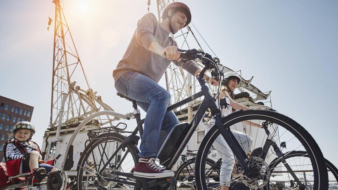 In Hamburg am Hafen fährt eine Familie mit ihren E-Bikes. In Hamburg am Hafen fährt eine Familie mit ihren E-Bikes.
