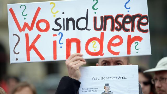 Bei einer Kundgebung für die Opfer von Zwangsadoptionen der DDR hält ein Mann vor dem Brandenburger Tor in Berlin ein Plakat mit der Aufschrift "Wo sind unsere Kinder?" hoch (April 2014).