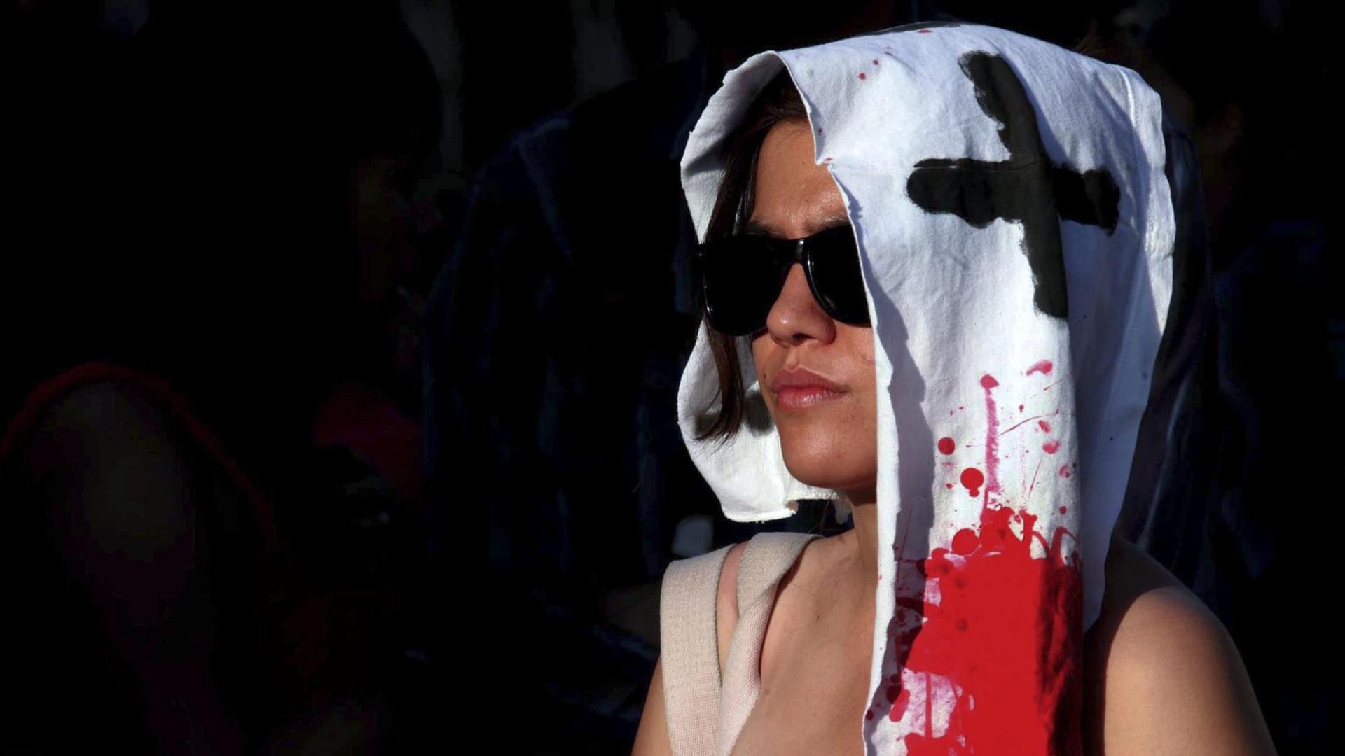 Eine Mexikanerin trägt ein mit roter Farbe und einem Kreuz bemaltes weißes Tuch über dem Kopf. Demonstranten fordern ein Ende der Gewalt in Mexiko. Eine Mexikanerin trägt ein mit roter Farbe und einem Kreuz bemaltes weißes Tuch über dem Kopf. Demonstranten fordern ein Ende der Gewalt in Mexiko.