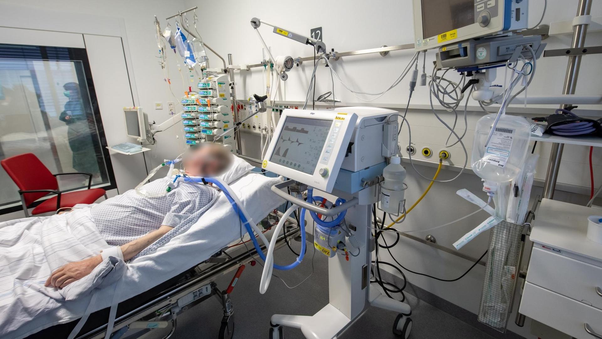 Ein Patient liegt in der Intensivstation an einem Beatmungsgerät. Ein Patient liegt in der Intensivstation an einem Beatmungsgerät.