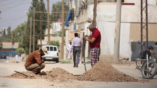 Zwei syrische Männer reparieren eine Wasserleitung in der Stadt Qamishli im Norden des Landes.