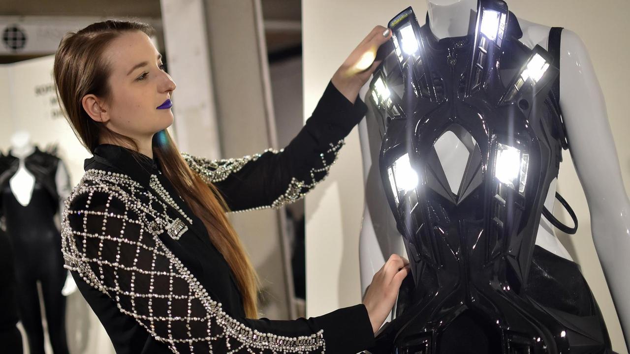 Eine junge Frau richtet am 18.01.2017 in Berlin bei der Modemesse Fashiontech im Rahmen der Berliner Modewoche eine Kreation des Designers Anouk Wipprecht aus den Niederlanden. Foto: Britta Pedersen/dpa-Zentralbild/dpa | Verwendung weltweit Eine junge Frau richtet am 18.01.2017 in Berlin bei der Modemesse Fashiontech im Rahmen der Berliner Modewoche eine Kreation des Designers Anouk Wipprecht aus den Niederlanden. Foto: Britta Pedersen/dpa-Zentralbild/dpa | Verwendung weltweit