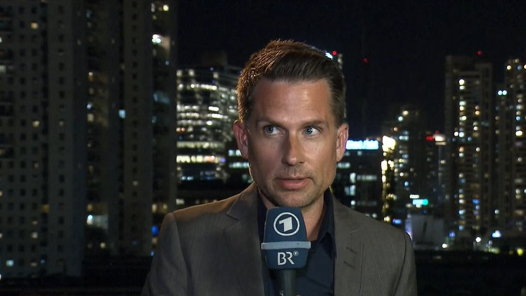 ARD-Korrespondent Mike Lingenfelser mit Mikrofon vor einem Nacht-Panorama Tel Avivs ARD-Korrespondent Mike Lingenfelser mit Mikrofon vor einem Nacht-Panorama Tel Avivs