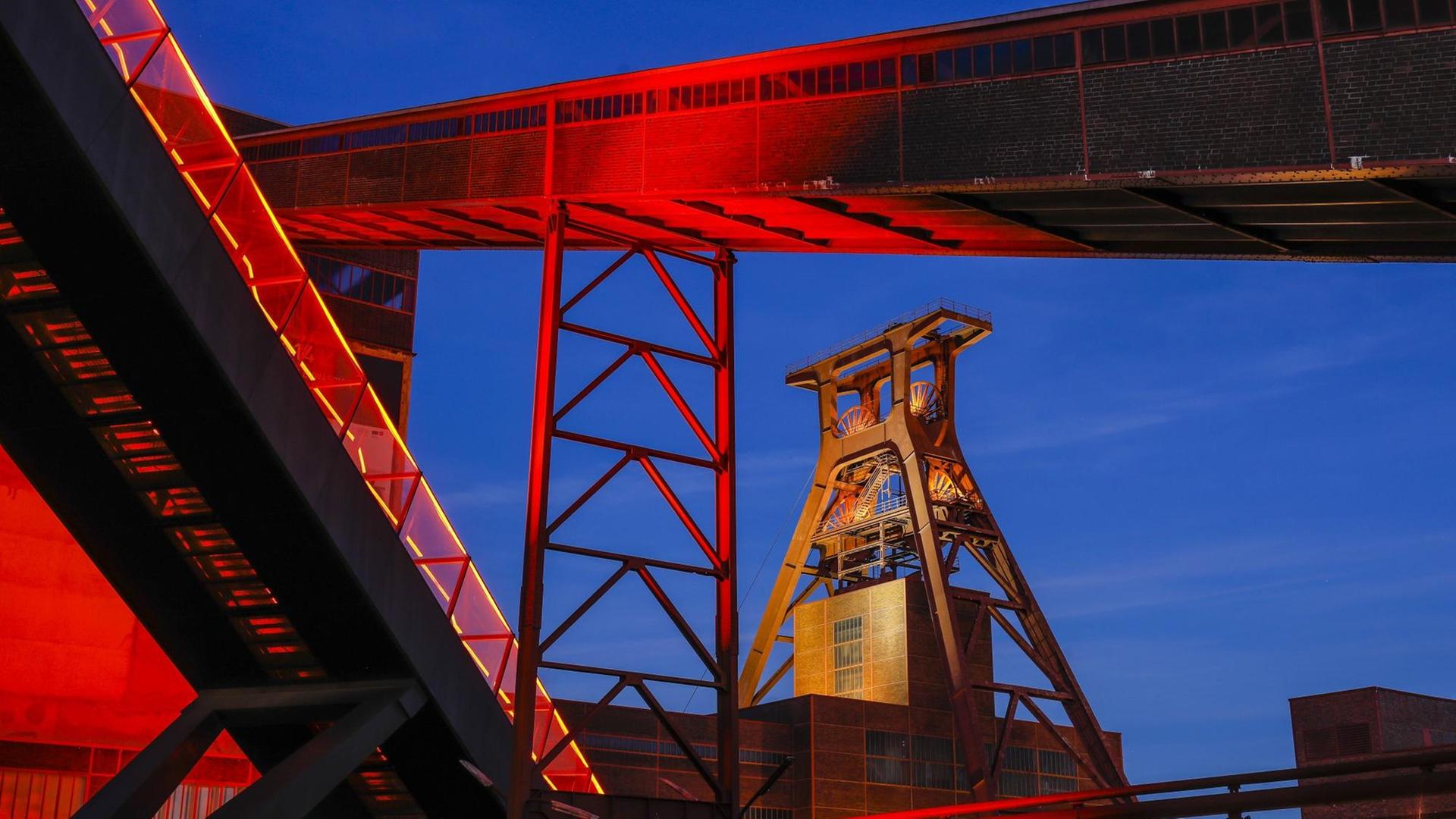 Das Foto zeigt die Zeche Zollverein in Essen. Der über das Ruhrgebiet hinaus bekannte Ausstellungs- und Veranstaltungsort ist in der Abenddämmerung rot illuminiert. Das Foto zeigt die Zeche Zollverein in Essen. Der über das Ruhrgebiet hinaus bekannte Ausstellungs- und Veranstaltungsort ist in der Abenddämmerung rot illuminiert.