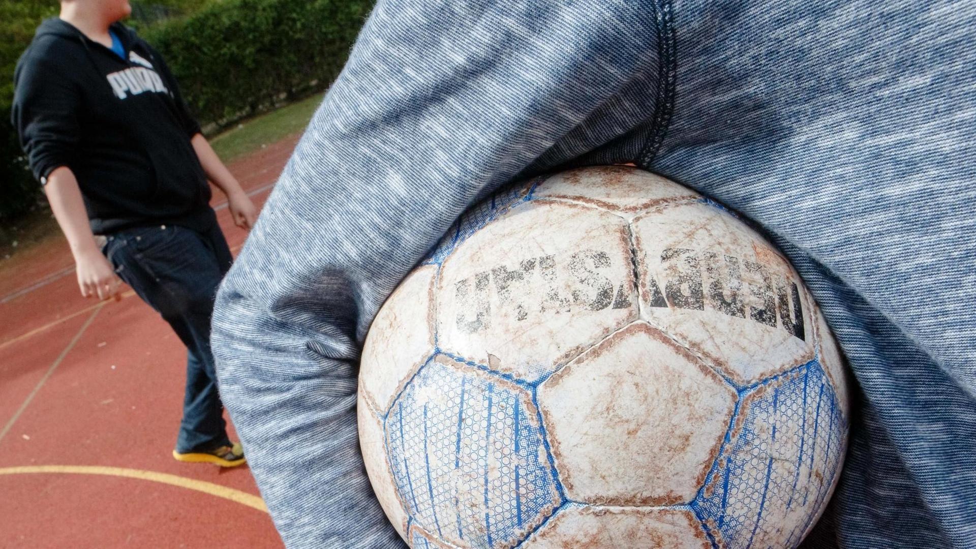 Ein Junge hält am 07.05.2015 in Hamburg auf einem Bolzplatz einen Fußball unter dem Arm. Ein Junge hält am 07.05.2015 in Hamburg auf einem Bolzplatz einen Fußball unter dem Arm.