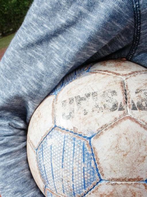Ein Junge hält am 07.05.2015 in Hamburg auf einem Bolzplatz einen Fußball unter dem Arm.