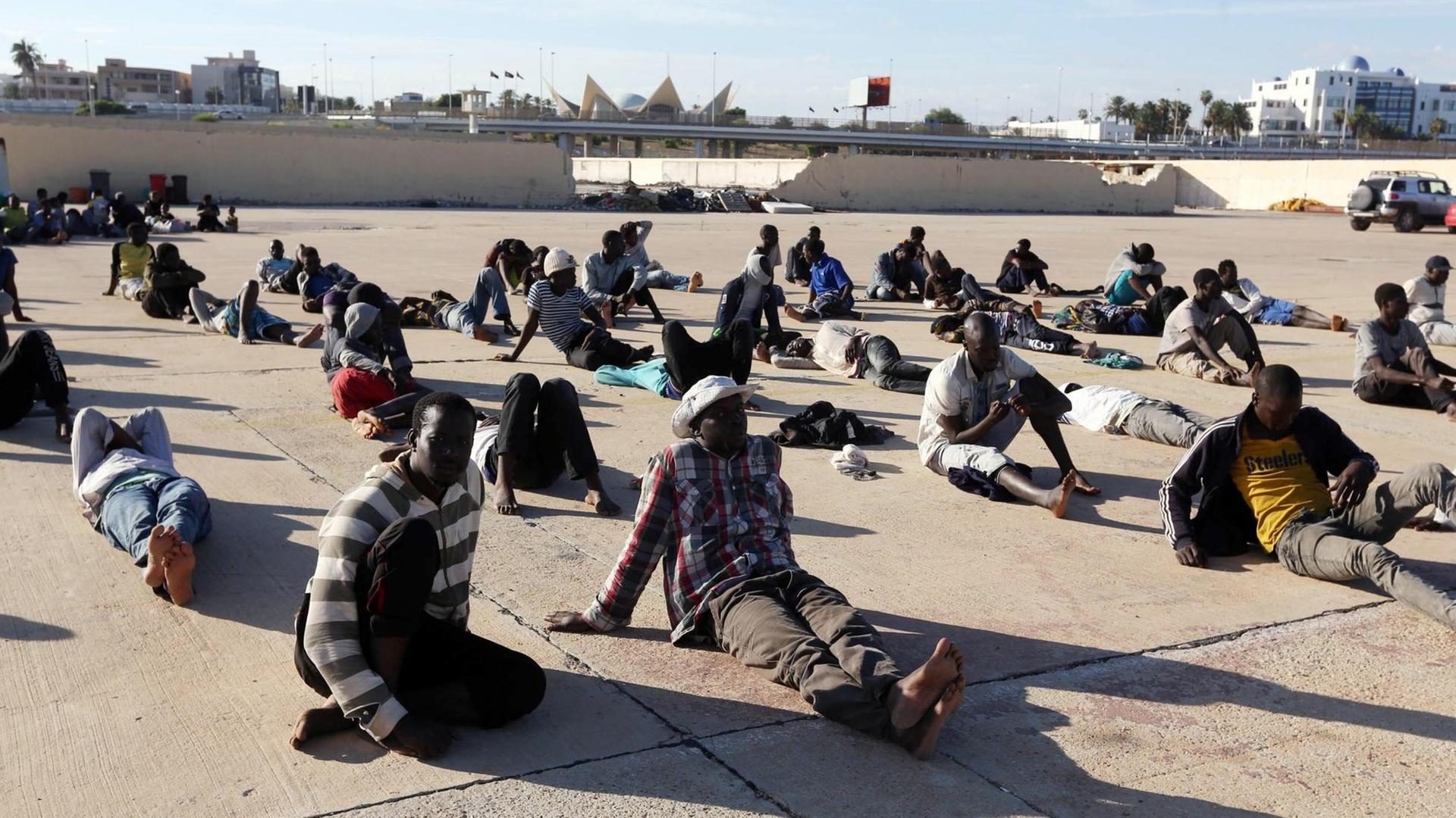 Flüchtlinge, die von der libyschen Küstenwache gerettet wurden, sitzen in Tripoli. Flüchtlinge, die von der libyschen Küstenwache gerettet wurden, sitzen in Tripoli.