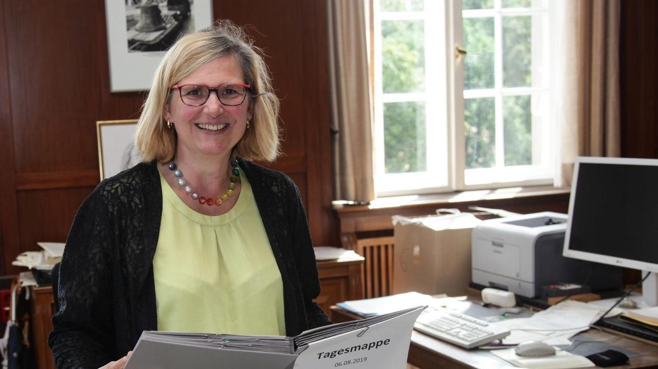 Angelika Schöttler posiert mit einem Ordner in der Hand für ein Foto. Angelika Schöttler posiert mit einem Ordner in der Hand für ein Foto.