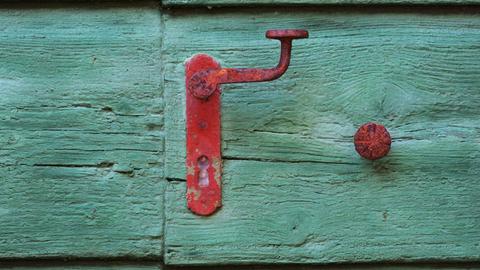 Eine grüne Holztür mit rotem Griff