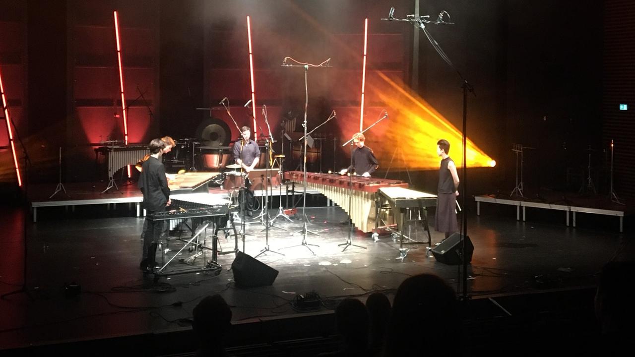 Vier Marimbaspieler im Konzert auf einer angestrahlten Bühne.