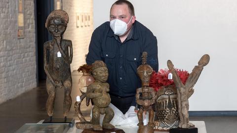Lars Frühsorge, Leiter der Lübecker Völkerkundesammlung, steht mit Mundschutz hinter afrikanischen Skulpturen.