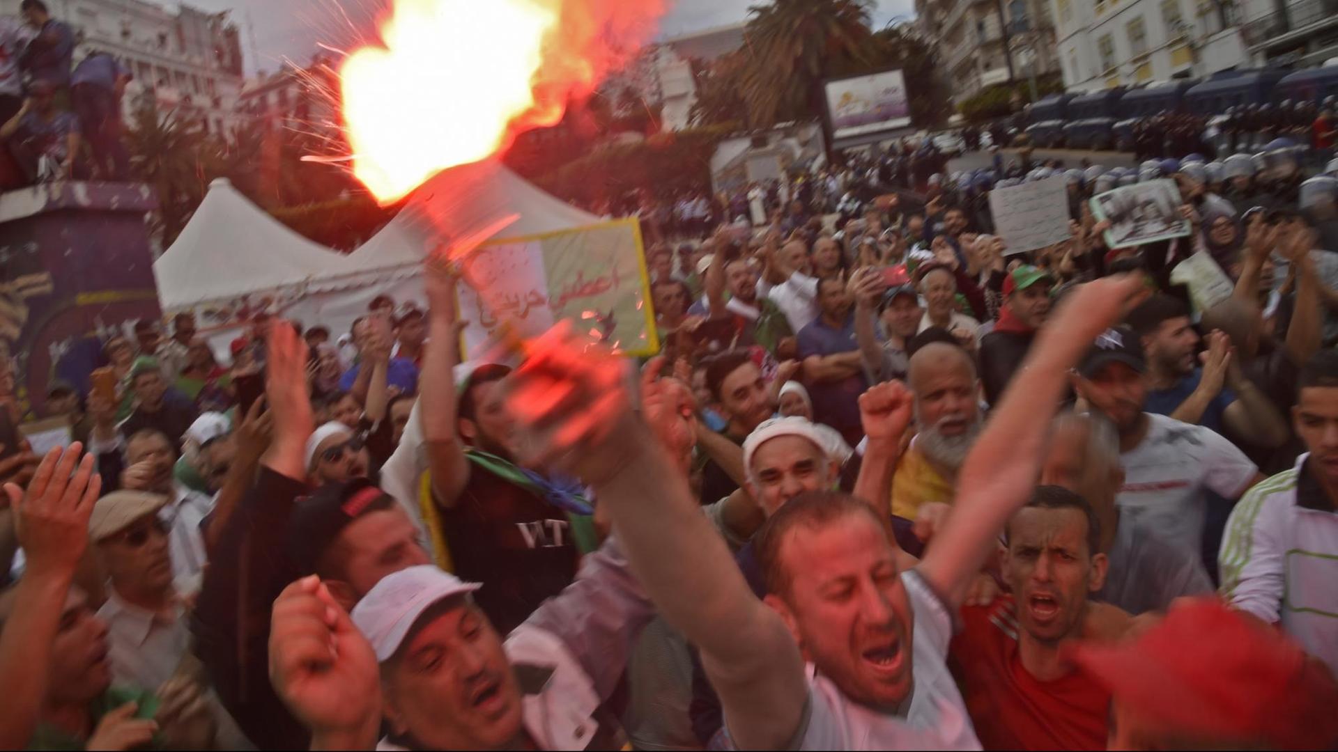 Demonstranten bilden Sprechchöre. Ein Mann im Vordergrund hält eine brennde Fackel in die Höhe. Demonstranten bilden Sprechchöre. Ein Mann im Vordergrund hält eine brennde Fackel in die Höhe.