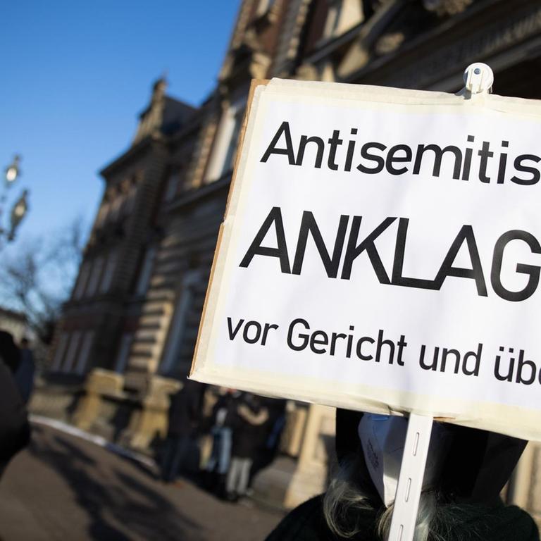 Eine Teilnehmerin einer Kundgebung hält eine Schild mit dem Text "Antisemitismus Anklagen vor Gericht und überall" vor dem Strafjustizgebäude in Hamburg 