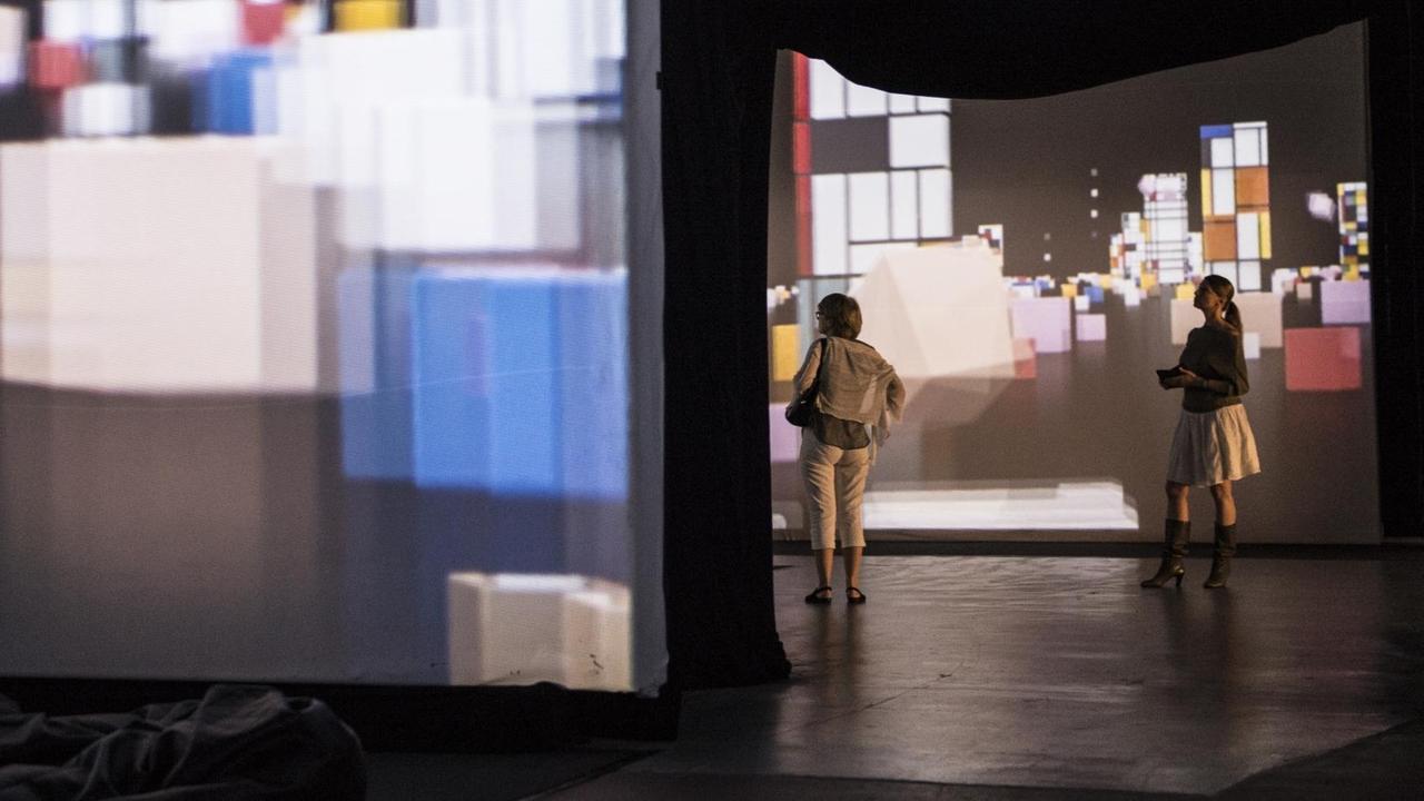 Besucher gehen am 20.07.2017 in Berlin in der Multimedia-Ausstellung "Von Monet bis Kandinsky" in der alten Münze Berlin an Werken von Piet Mondrian vorbei. Ab dem 21.07.2017 können sich die Besucher die Werke bei Musik vom Band anschauen.