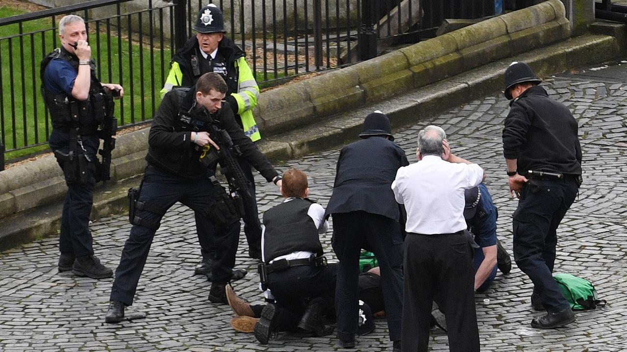 Polizisten stehen am 22.03.2017 in der Nähe des britischen Parlaments in London (Großbritannien) um eine auf dem Boden Liegende Person.