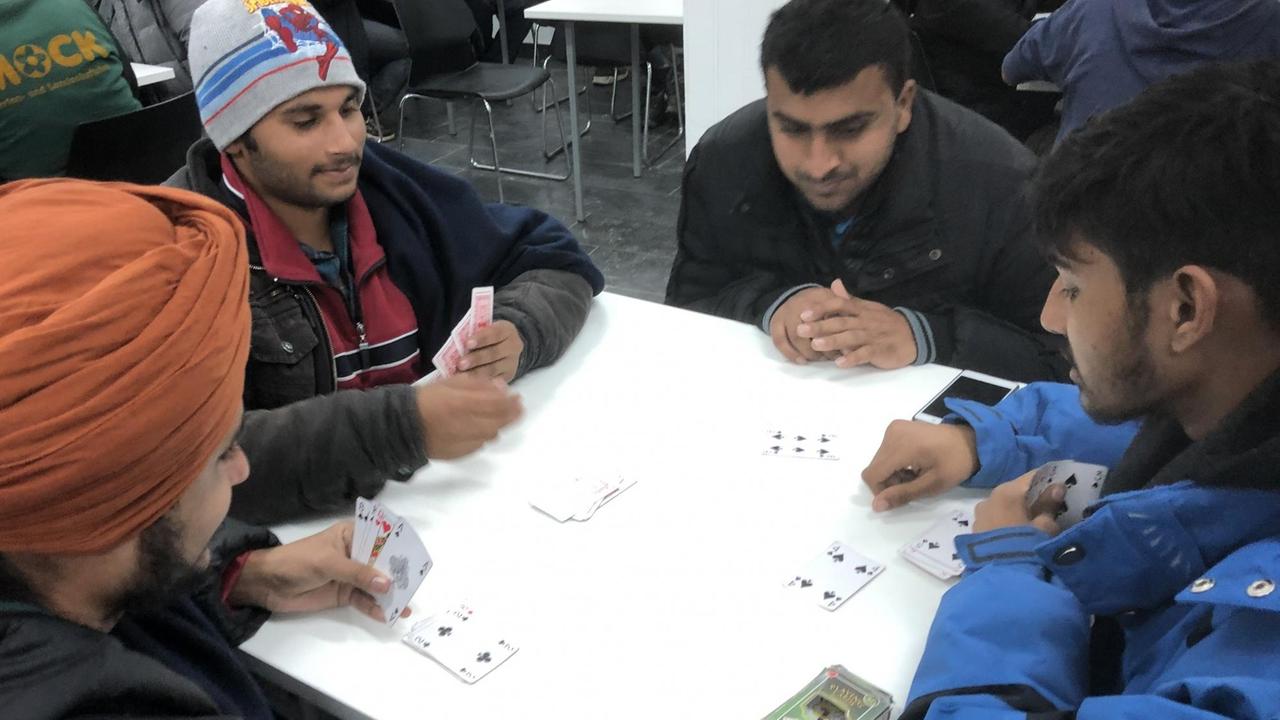 Flüchtlinge spielen Karten an einem Tisch Flüchtlinge spielen Karten an einem Tisch