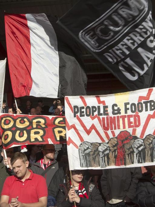 Fans von FC United of Manchester schwenken Banner im Broadhurst Park Stadion.