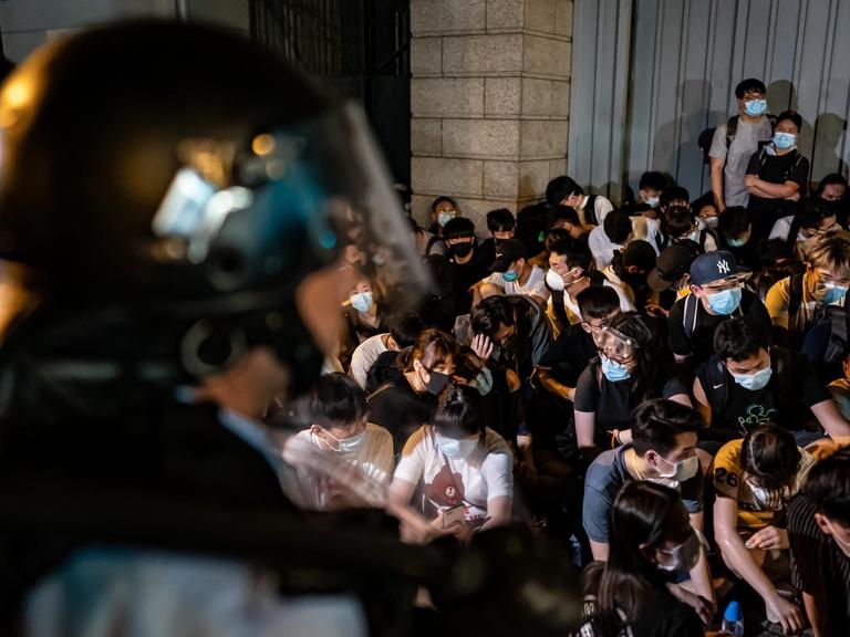 In Gewahrsam genommene Demonstranten in Hongkong, im Vordergrund ist der Helm eines Polizisten zu sehen, aufgenommen am 10. Juni 2019