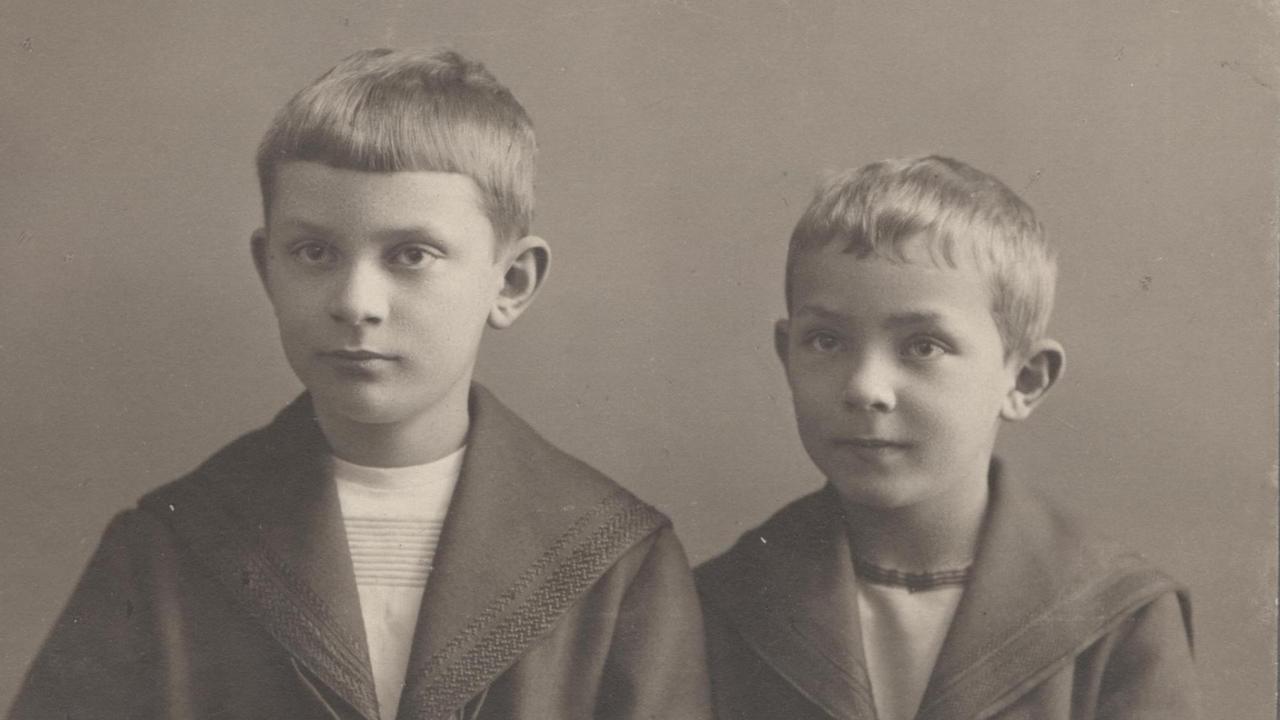 Ein verblichenes Schwarzweißfoto: Zwei Jungen in Matrosenanzügen schauen an der Kamera vorbei; der linke, etwas ältere, mit ernstem Gesicht.