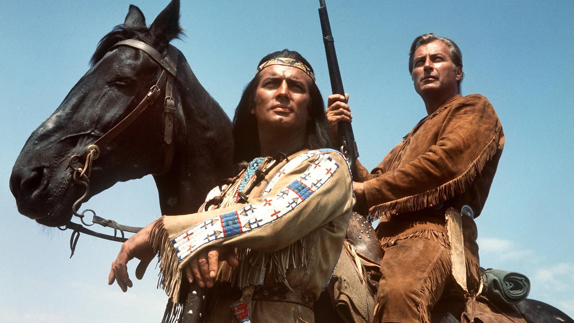 Pierre Brice (l) als Apachen-Häuptling Winnetou und Lex Barker als sein Blutsbruder Old Shatterhand in einer Szene des Karl-May-Films "Im Tal des Todes". Lex Barker sitzt auf einem Pferd mit einem Gewehr in der Hand. Beide schauen in die Ferne. Pierre Brice (l) als Apachen-Häuptling Winnetou und Lex Barker als sein Blutsbruder Old Shatterhand in einer Szene des Karl-May-Films "Im Tal des Todes". Lex Barker sitzt auf einem Pferd mit einem Gewehr in der Hand. Beide schauen in die Ferne.