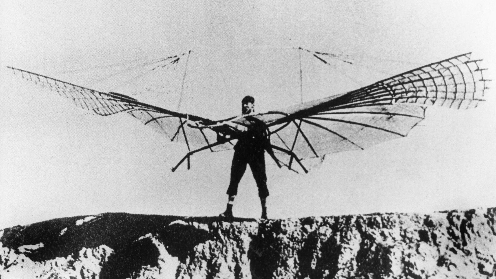 Otto Lilienthal bei einem seiner zahlreichen Gleitflugversuche. Er steht mit einem Gleitschirm auf vor einem Abhang Otto Lilienthal bei einem seiner zahlreichen Gleitflugversuche. Er steht mit einem Gleitschirm auf vor einem Abhang
