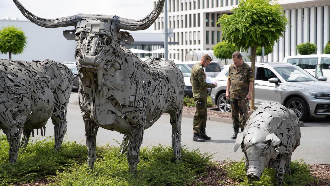 Bundeswehrangehörige stehen auf dem Betriebsgelände von Tönnies. Im Vordergrund Statuen von einem Stier und einem Schwein. Bundeswehrangehörige stehen auf dem Betriebsgelände von Tönnies. Im Vordergrund Statuen von einem Stier und einem Schwein.