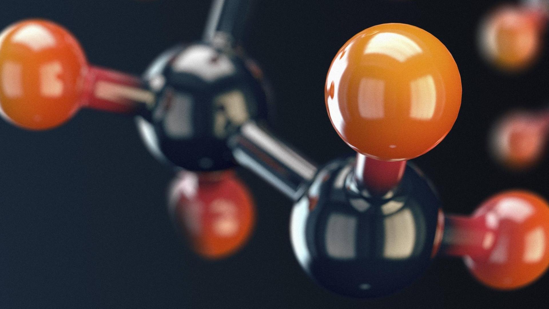 Ein glänzendes Modell eines Moleküls mit orangenen und schwarzen Atomen. Ein glänzendes Modell eines Moleküls mit orangenen und schwarzen Atomen.