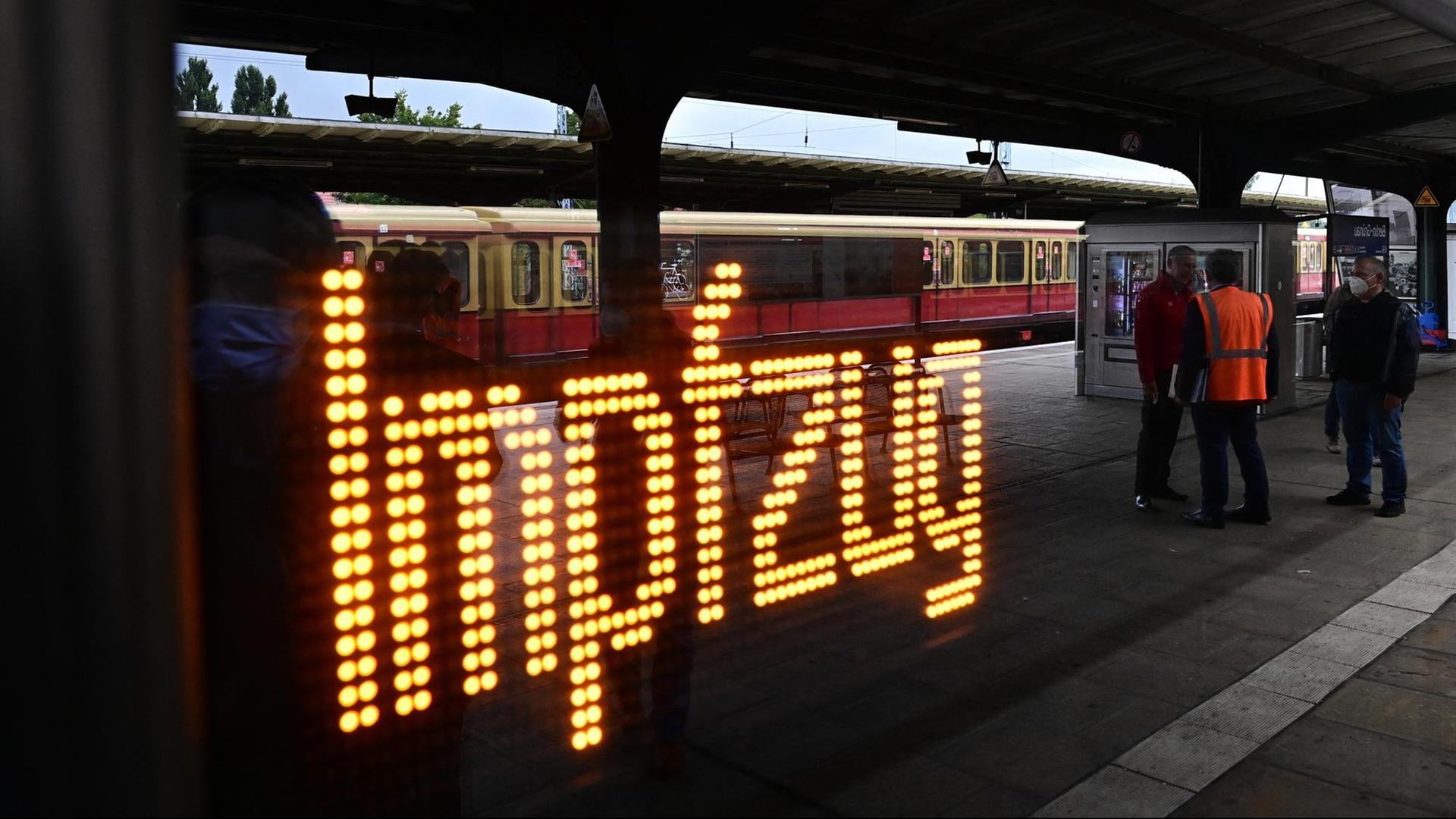 Hinter einem Fenster der Berliner S-Bahn leuchtet das Wort "Impfzug" auf, in der Spiegelung ist ein halb leerer Bahnsteig zu sehen.