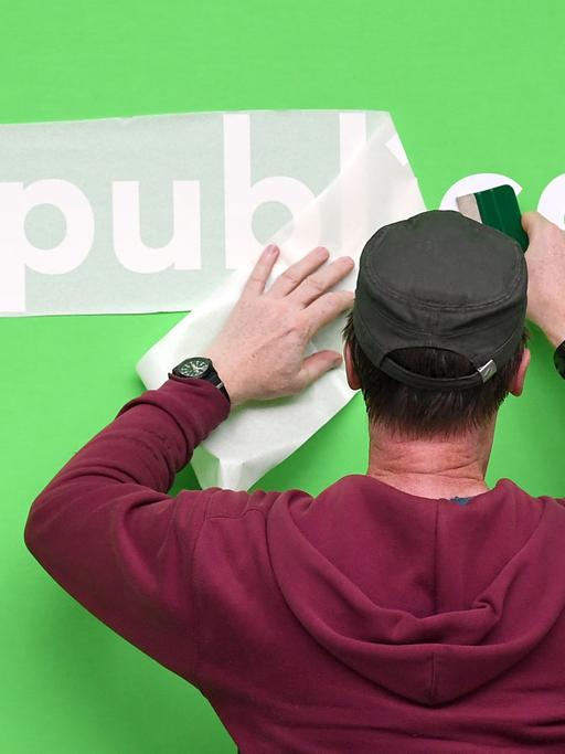 Ein Mann klebt einen Schriftzug für die Re:publica 2018 in Berlin