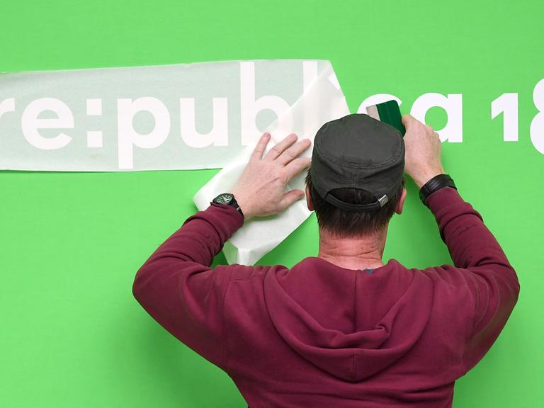 Ein Mann klebt einen Schriftzug für die Re:publica 2018 in Berlin
